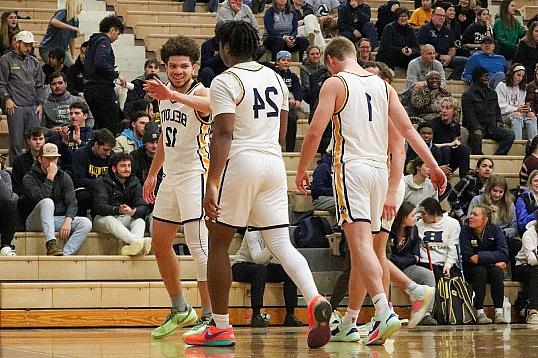 Buccaneer mens basketball team members offer each other high fives during a game.