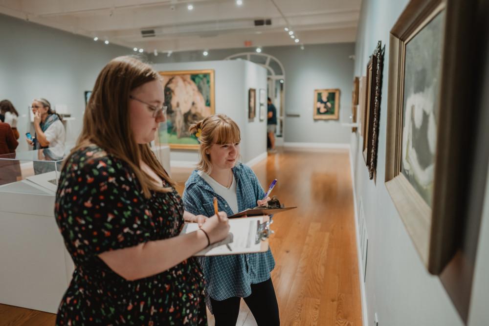 Two students studying artwork inside the Wright Museum of Art.